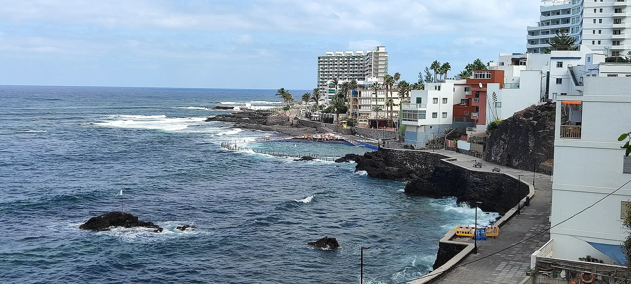 Piscina marina, palmeras y edificios frente al mar en Punta del Hidalgo