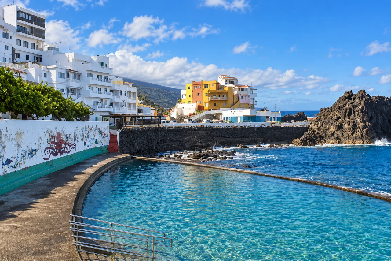 Piscina costera bajo las casas de colores del pueblo de El Pris